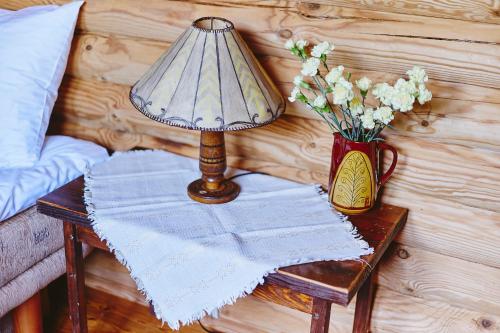 a table with a lamp and a vase of flowers on it at Slow House Gaładuś in Radziucie