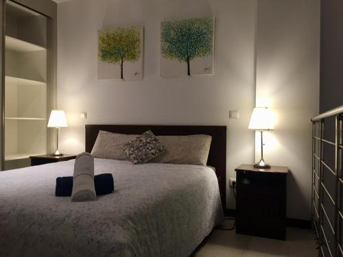 a bedroom with a bed with two lamps and two trees on the wall at Lujoso Loft La Moraleja in Madrid