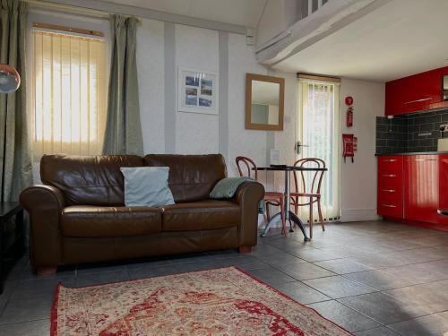 a living room with a brown couch and a table at Barnacle Barn, North Norfolk in Roughton