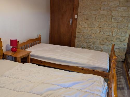 two beds in a room with a stone wall at Charmant gîte rénové en 2015, au cœur de l'Argonne, entre Verdun et Châlons-en-Champagne - FR-1-585-21 in Futeau