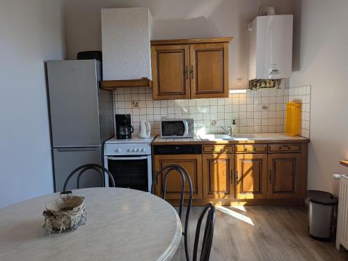 a kitchen with wooden cabinets and a table and a refrigerator at Gîte confortable dans l'ancien presbytère de Futeau, 3 chambres, jardin, WiFi, entre Verdun et Châlons - FR-1-585-13 in Futeau
