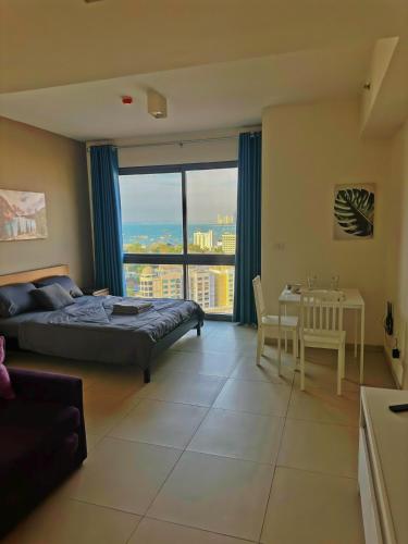 Un dormitorio con una cama, un escritorio y una mesa. en Unixx Sea view, en Pattaya South