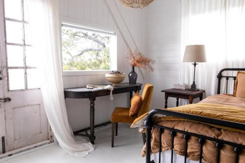 a bedroom with a bed and a table with a window at The Reads Freycinet - Water Front Property in Coles Bay