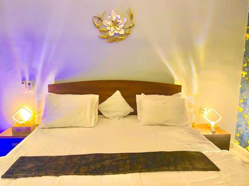 a bedroom with a white bed with a flower clock on the wall at Private in Dargai