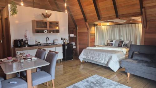 a bedroom with a bed and a table and a kitchen at Pousada Sol chalé in Blumenau