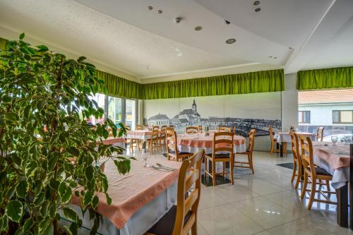 a restaurant with tables and chairs and a painting of a city at Hotel Samaria in Šamorín