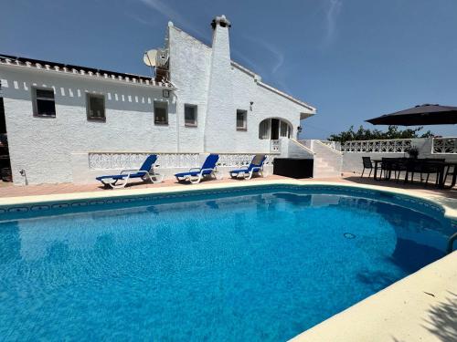 a swimming pool with blue chairs and a house at Wonderful villa with private pool summer kitchen in El Tosalet