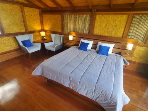 a bedroom with a large bed with blue pillows at MAYU PATANPI Amazon Lodges in Tarapoto