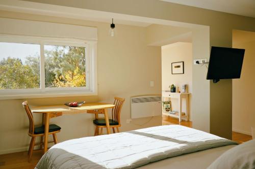a bedroom with a bed and a table and a window at Kowhai Studio -private opposite golf course in central Wanaka in Wanaka