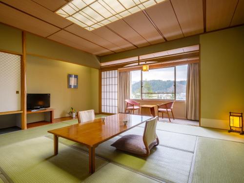 a living room with a table and chairs and a television at Hotel Kazuno in Kazuno