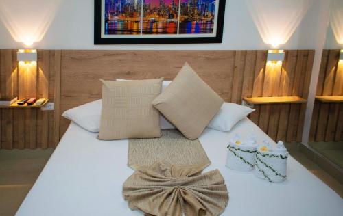 1 cama blanca con almohadas y una foto en la pared en Sixth House Suite, en Cali