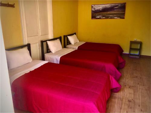 two beds in a room with red and white sheets at Holidays Hostel Arequipa in Arequipa