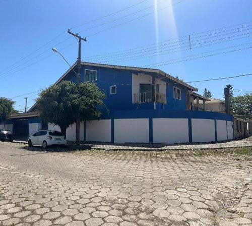 a blue and white building with a car parked in front at Pousada Pérolas de Peruíbe in Peruíbe