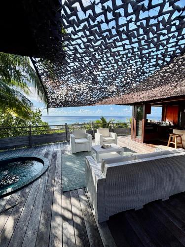 a patio with white furniture on a wooden deck at Villa de Luxe Tianee Le Légends, vue panoramique Ocean ,3 Chambres, 2 Salles de bain, piscine, jacuzzi, salle de sport in Irioa