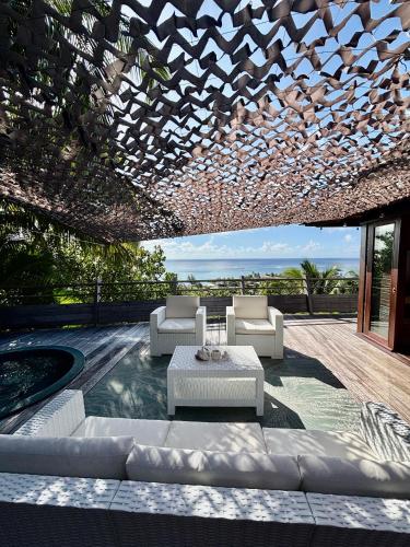 a patio with white couches and a table at Villa de Luxe Tianee Le Légends, vue panoramique Ocean ,3 Chambres, 2 Salles de bain, piscine, jacuzzi, salle de sport in Irioa