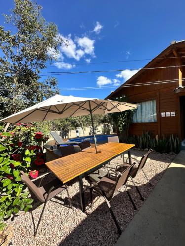 a wooden table and chairs under an umbrella at Woodhouse Tranquilidade e Conforto no Paraíso, piscina aquecida e ar condicionado in Alto Paraíso de Goiás