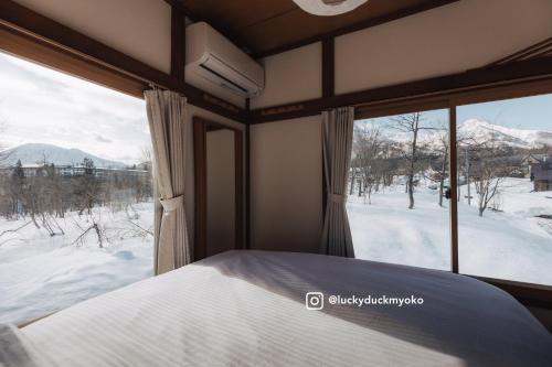 a bedroom with a bed and a view of a snow covered field at Lucky Duck Cabin Myoko in Myoko