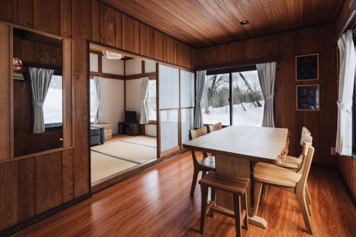 a dining room with wooden walls and a table and chairs at Lucky Duck Cabin Myoko in Myoko