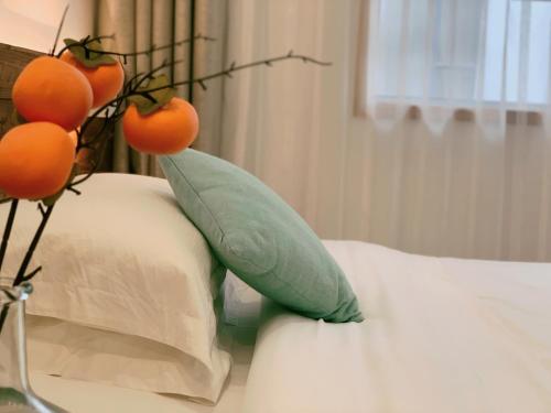 a green vase with oranges on top of a bed at Zhangjiajie One Art Guesthouse in Zhangjiajie
