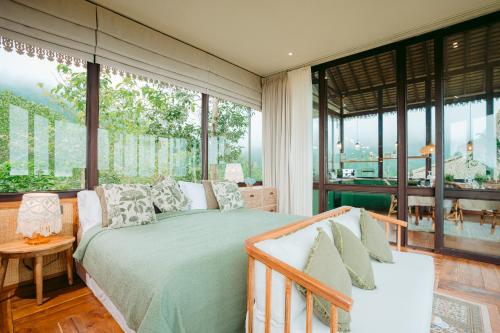 a bedroom with a bed and large windows at The Little Hill Suite in Munduk