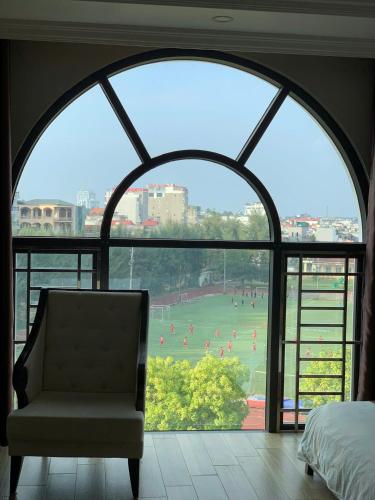 a bedroom with a large window with a chair and a soccer field at Asean Hotel in Hải Dương