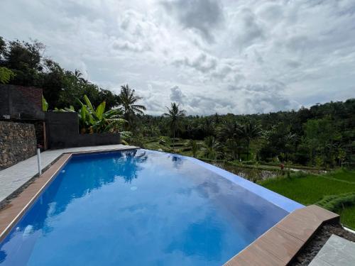 a large swimming pool with blue water in a backyard at Nona Lodge in Tetebatu