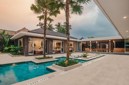 an exterior view of a house with a swimming pool and palm trees at Villa Dune in Ubud