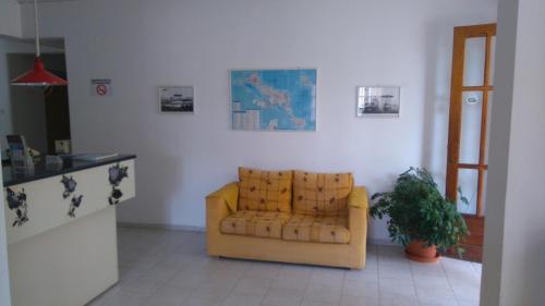 a living room with a yellow couch and a plant at Hotel Aidipsos in Loutra Edipsou