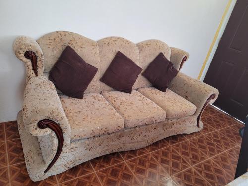 a couch with pillows sitting on a floor at Pacific View Apartment in Roseau