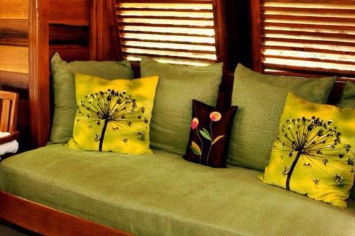 a green couch with pillows on top of it at Acajou Hotel in Grande Riviere