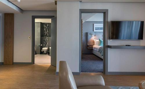 a living room with a bed and a television at Krystal Beach Hotel in Gordonʼs Bay