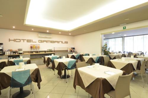 un restaurante con mesas y sillas en una cafetería en Hotel Gambrinus, en Lignano Sabbiadoro