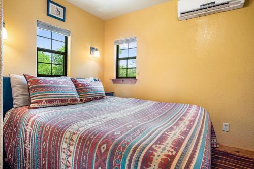 a bedroom with a bed and two windows at Bandera Stronghold - Crazy Horse Cabin in Bandera