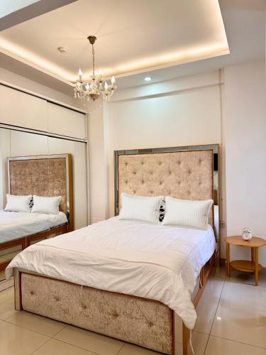 a bedroom with two beds and a chandelier at Cozy 1BR Apartment with Home Office at The Nest Jakarta Barat in Jakarta