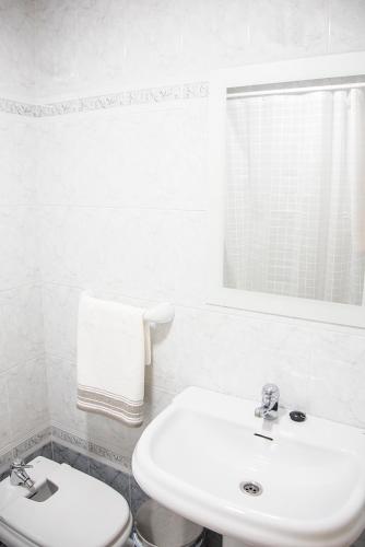 a white bathroom with a sink and a toilet at Alojamiento Miramar in Santoña