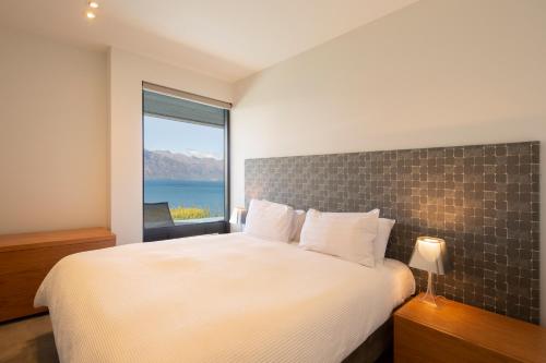 a bedroom with a large bed with a large window at Aspen Grove by Sotheby's Luxury Rental Homes in Queenstown