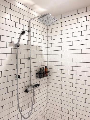 a shower in a bathroom with white tiles at Hayama Farmstead Inn in Hayama
