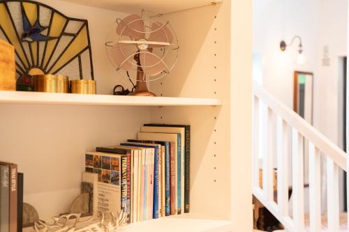 a book shelf with books and a fan at Hayama Farmstead Inn in Hayama