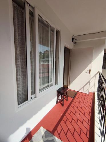 a balcony with windows and a red rug at ARISAN Bed and Breakfast in Shillong