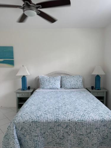 a bedroom with a bed with blue pillows and a ceiling fan at Sunset Cove - Vacation In Paradise! in Nassau