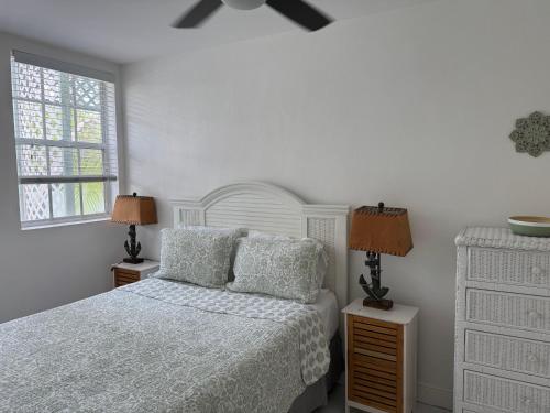 a white bedroom with a bed and two lamps at Sunset Cove - Vacation In Paradise! in Nassau
