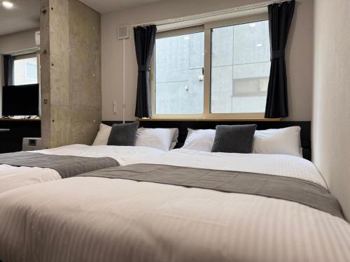 two beds in a room with a window at エクセル北円山 in Sapporo