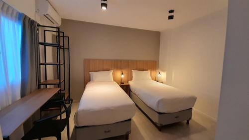 a hotel room with two beds and a desk and a desk at Casa Be Suites in Rosario
