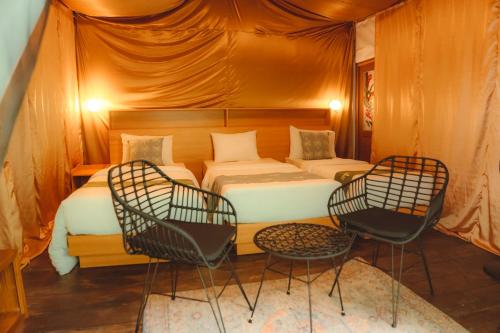 a bedroom with a bed and chairs in a tent at Glamping tent in Pelaga Eco Park in Patjung
