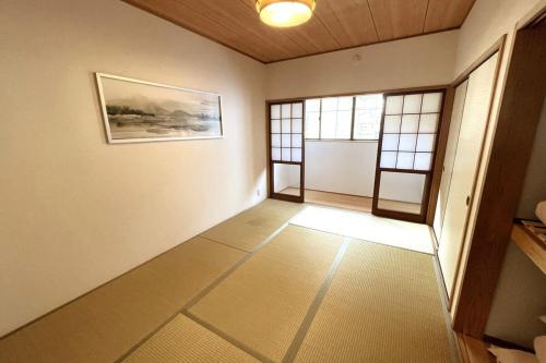 an empty hallway with two windows and a painting on the wall at Oneness House Kumamoto in Kumamoto