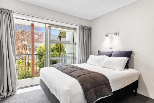a bedroom with a bed and a large window at ASURE Brookvale Motel in Wanaka