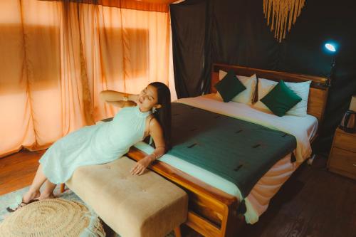 a young girl jumping on a bed in a room at Glamping tent in Pelaga Eco Park in Patjung