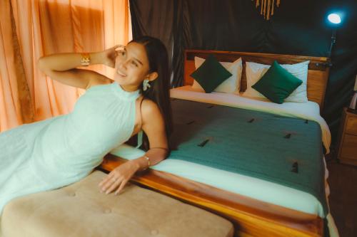 a woman laying on a bed in a bedroom at Glamping tent in Pelaga Eco Park in Patjung