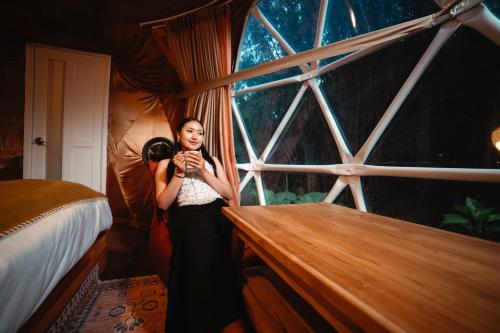 a woman taking a picture in front of a window at Glamping tent in Pelaga Eco Park in Patjung