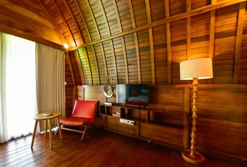 a living room with a television and a red chair at The Lumbung Wood Villa in Seminyak